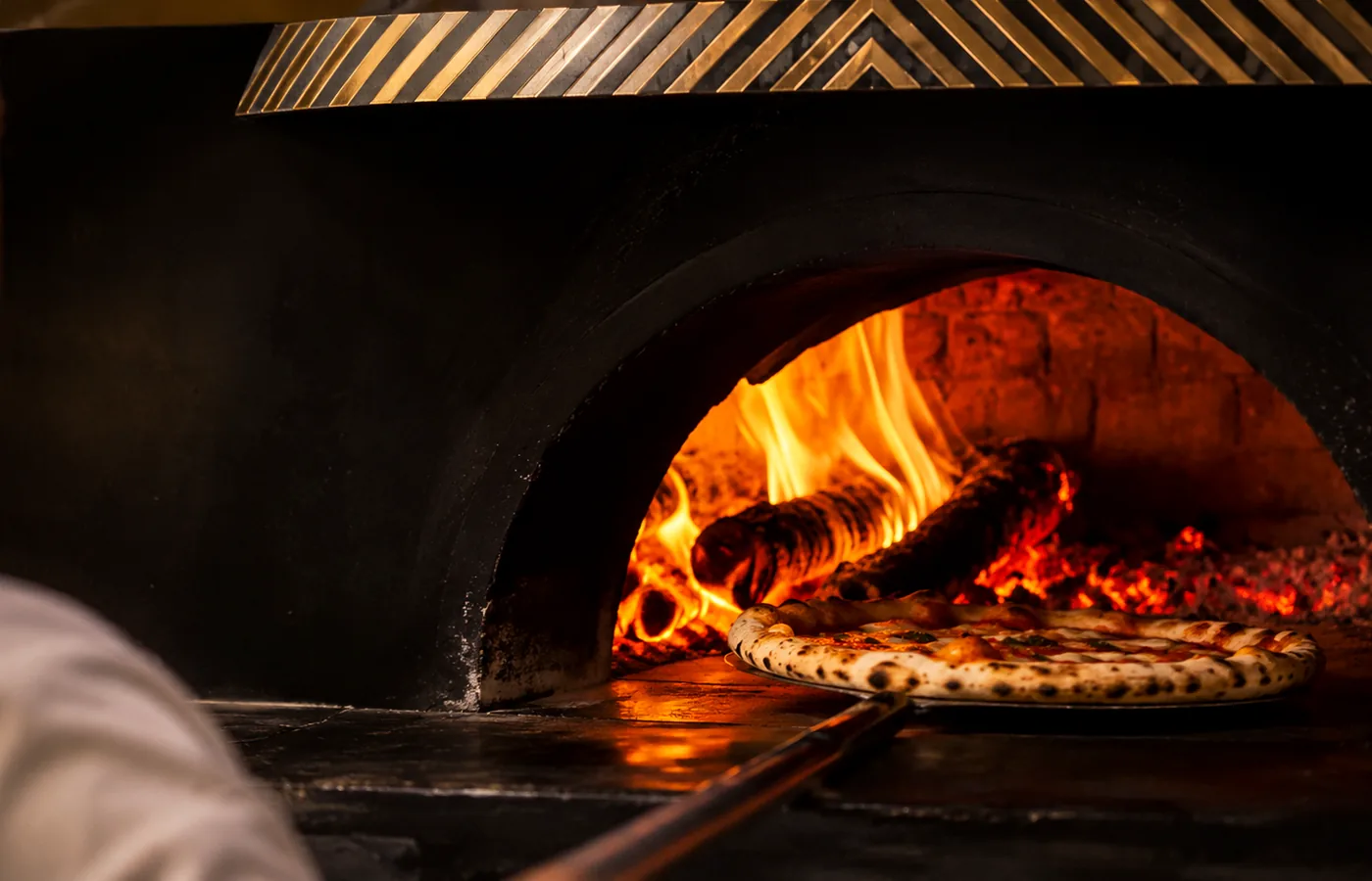 Forno a lenha real da Dom Pillone aceso, com pizza sobre a pá